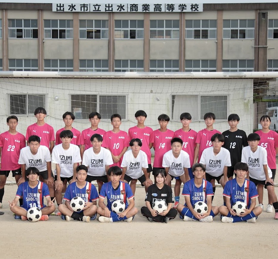 校舎前のグラウンドで集合写真に納まる出水商業高等学校サッカー部の部員