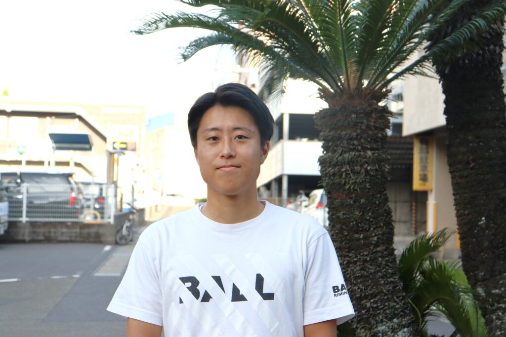白いTシャツ姿で屋外に立つ鶴結びの新メンバー